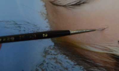 Paintbrush applying paint to an oil painting.